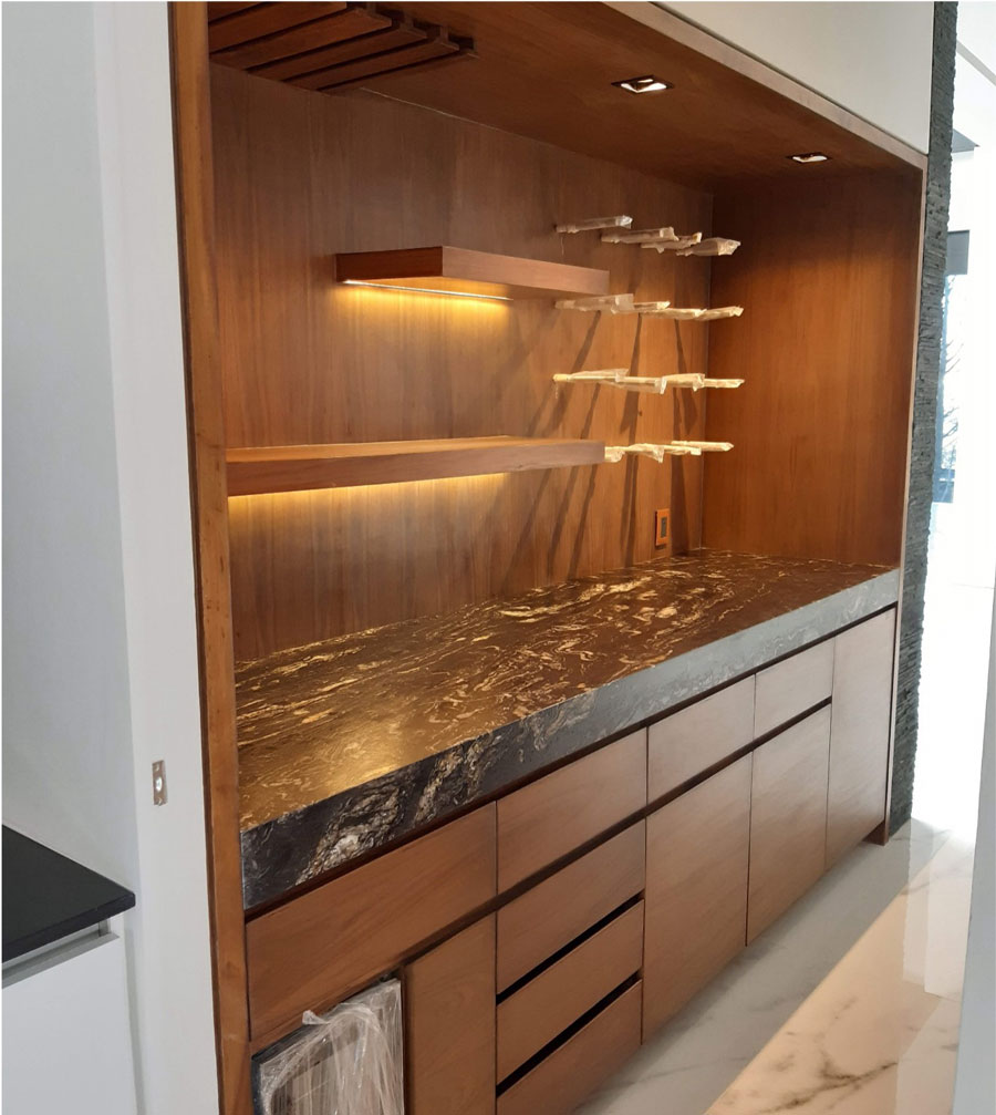 Mueble de cocina integral con acabados en madera de nogal, cubierta de mármol veteado, iluminación LED bajo repisas, estantería flotante y cajones con herrajes ocultos